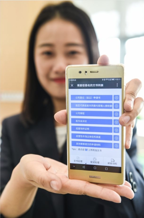 4 在南京市栖霞区商事登记服务大厅，工作人员展示以微信公众号为平台的“不见面审批”系统（新华社记者 李博 摄）.JPG