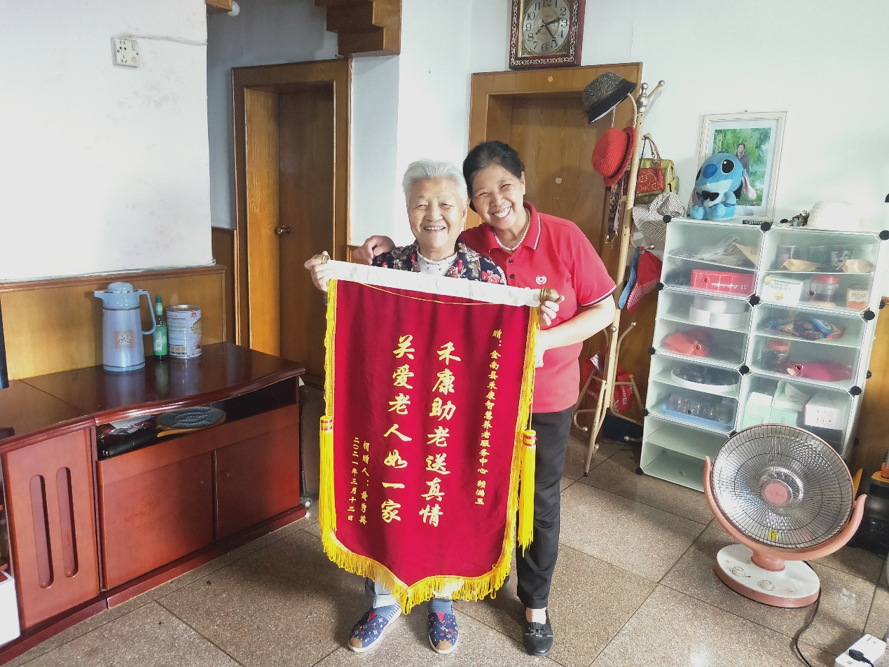常年患病的黄秀英老人将印有"关爱老人如一家"的锦旗,送给了江西省